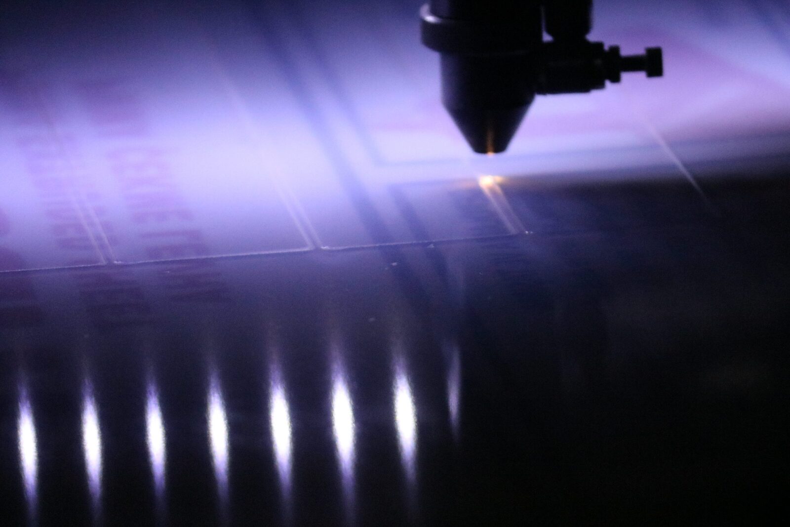 Laser cutting head cutting sheet metal on the Surtas-USA fabrication floor